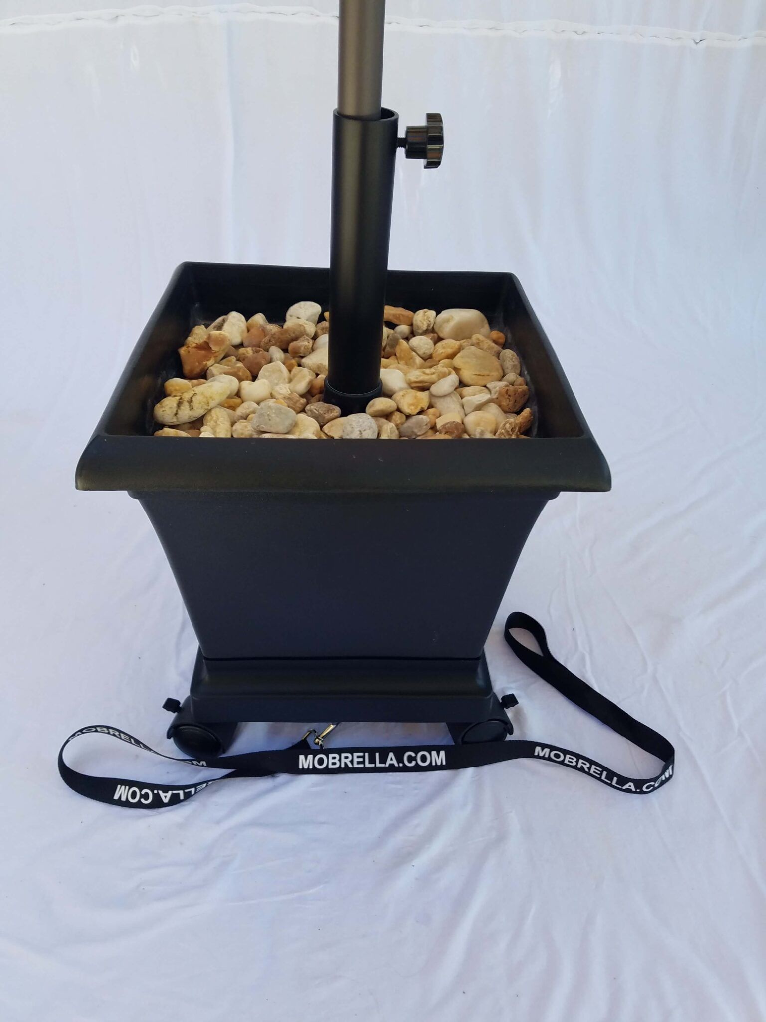 A black planter filled with rocks and an umbrella holder