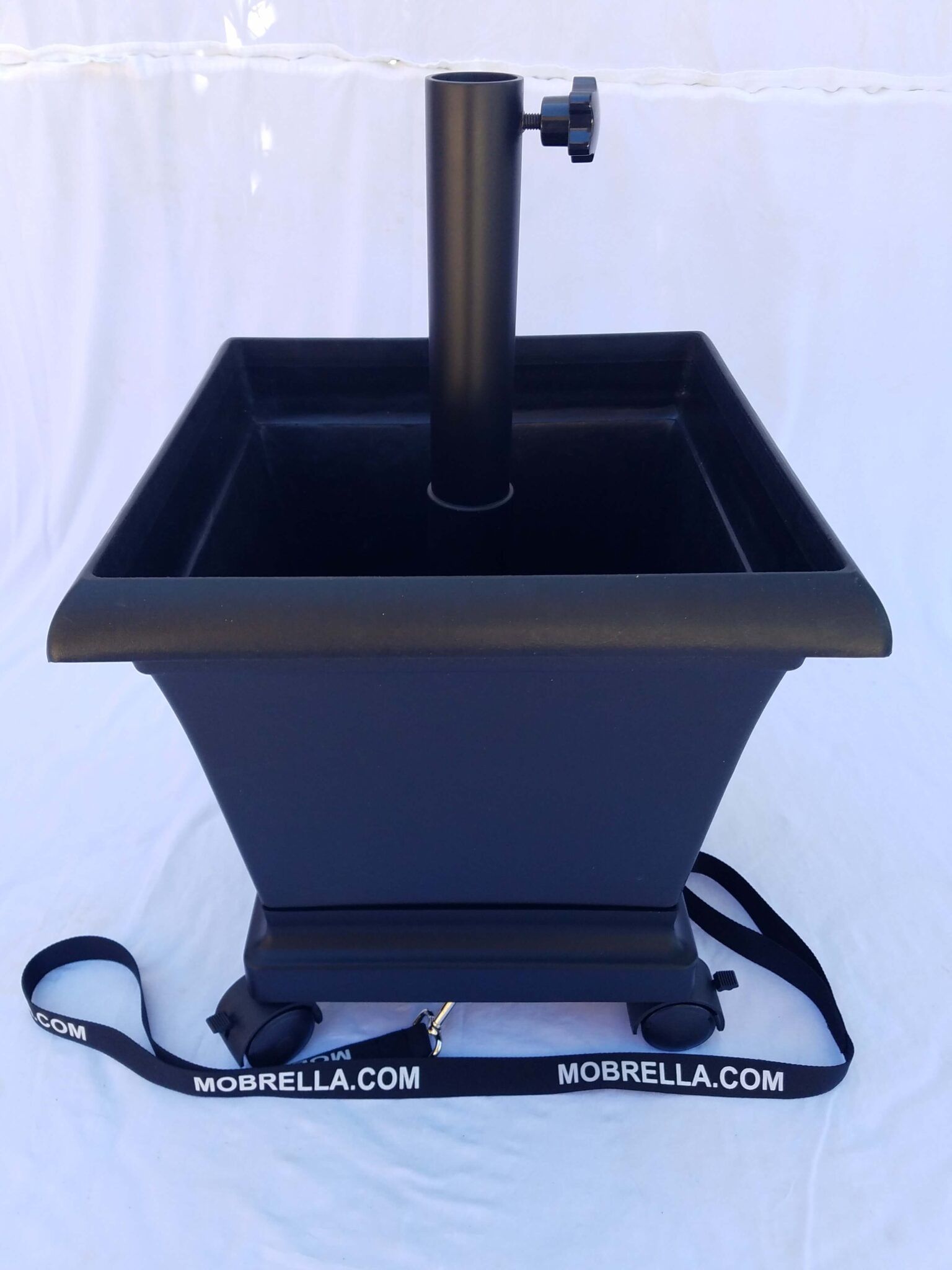 A black planter with an umbrella holder attached to it
