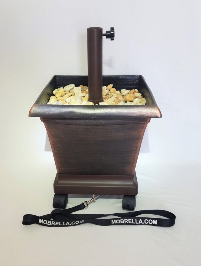 A brown planter filled with rocks and an umbrella holder