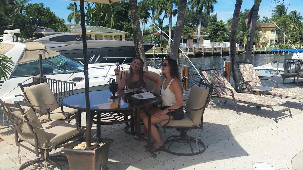 Two women are sitting at a table on the beach.