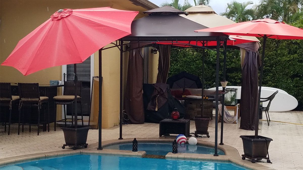 A pool with two red umbrellas and a canopy over it