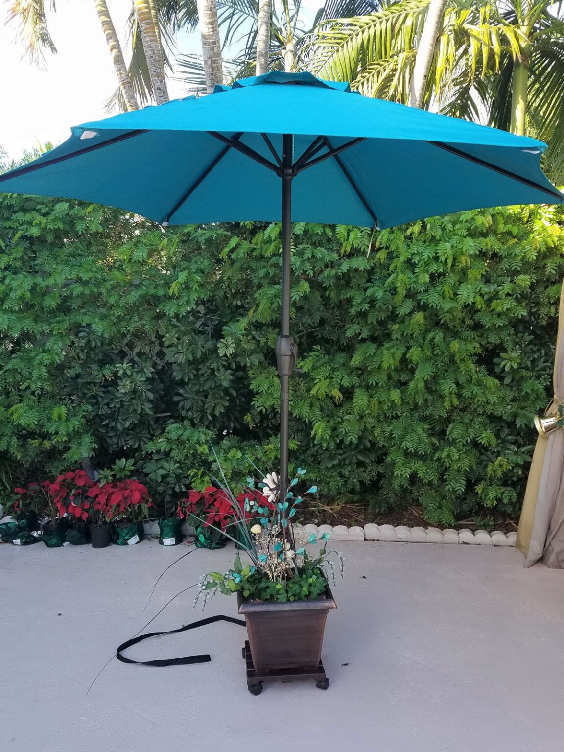 A blue umbrella is sitting on a patio next to a potted plant.