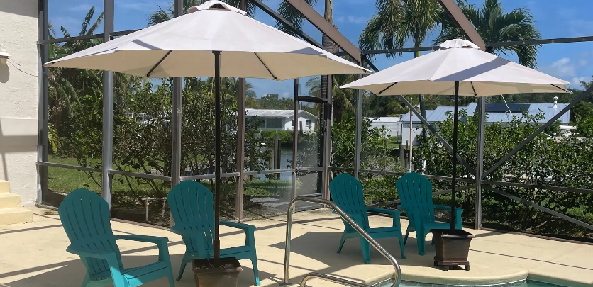 A patio with chairs and umbrellas next to a pool.