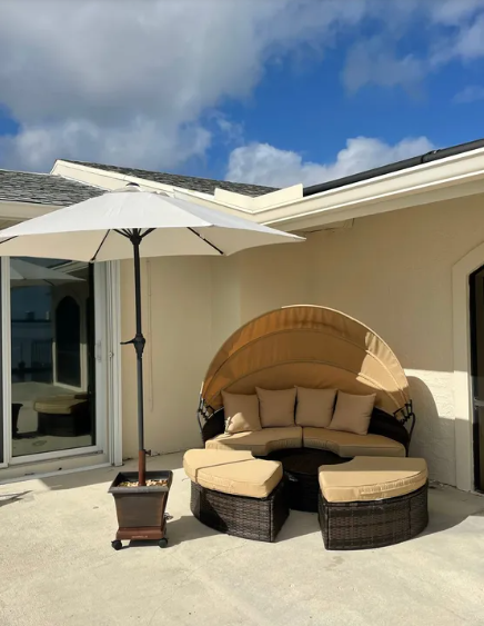 A patio with a round couch and an umbrella