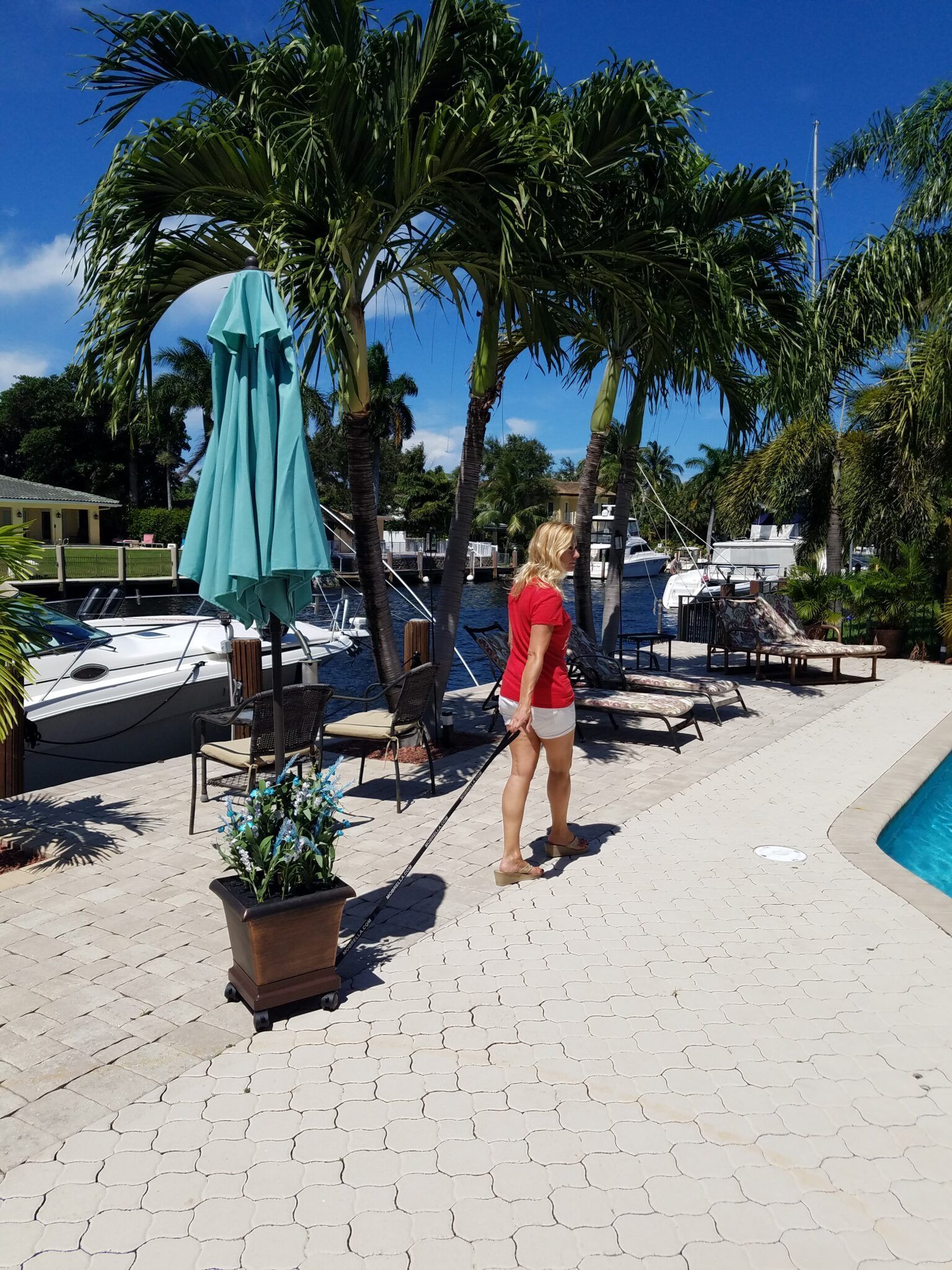 A woman in a red shirt is standing next to a pool