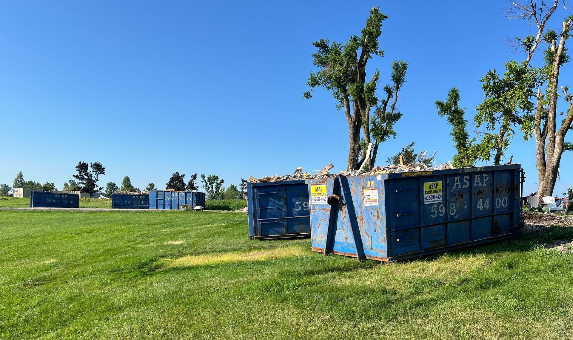 A couple of dumpsters rentals are sitting on top of a lush green field.