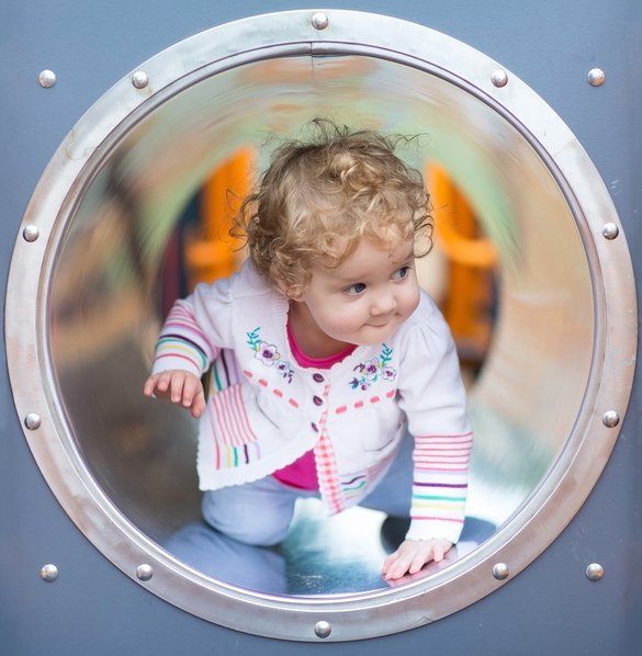 Adorable funny baby girl hiding on a playground