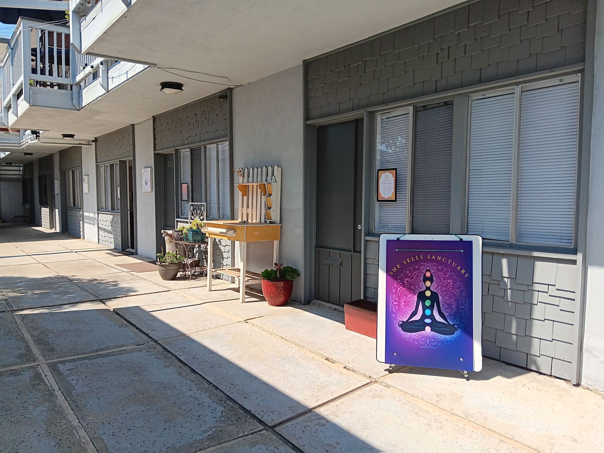 Courtyard with a sign for a meditation center. A person is in a lotus position, with chakra colors displayed.