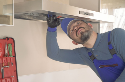 A person is cleaning a kitchen hood with a blue cloth. A person is cleaning a kitchen hood with a blue cloth.