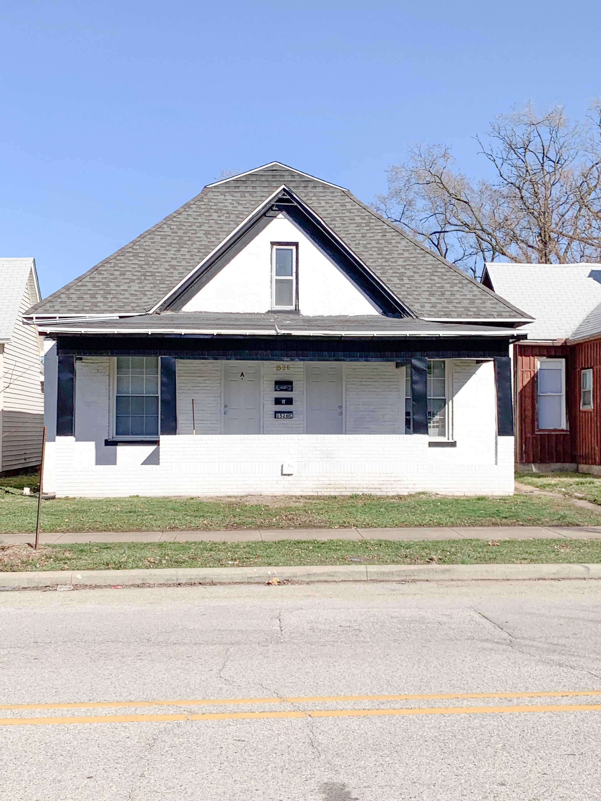 A white house with a gray roof sits on the side of the road