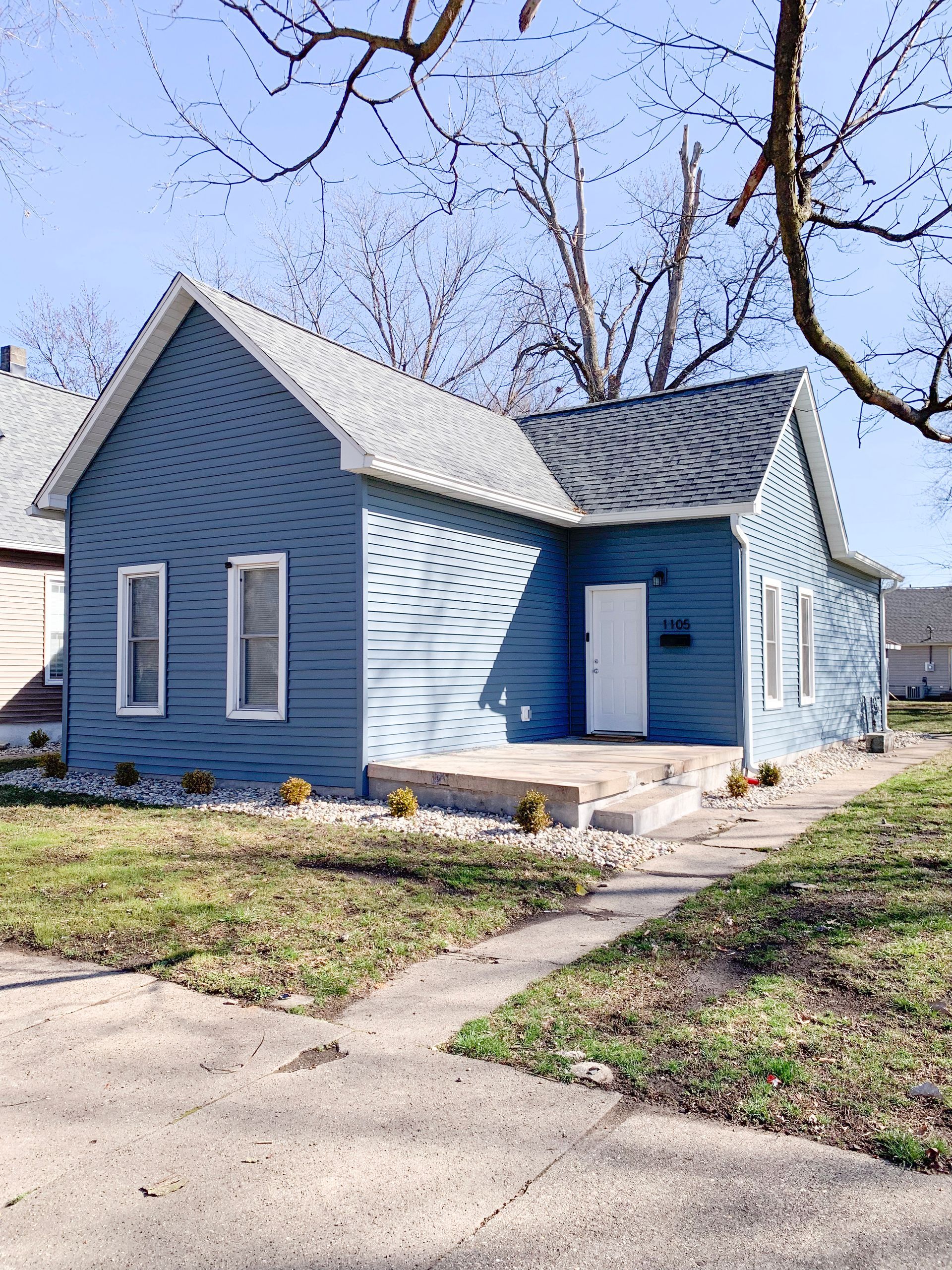 A small blue house with a gray roof and a white door