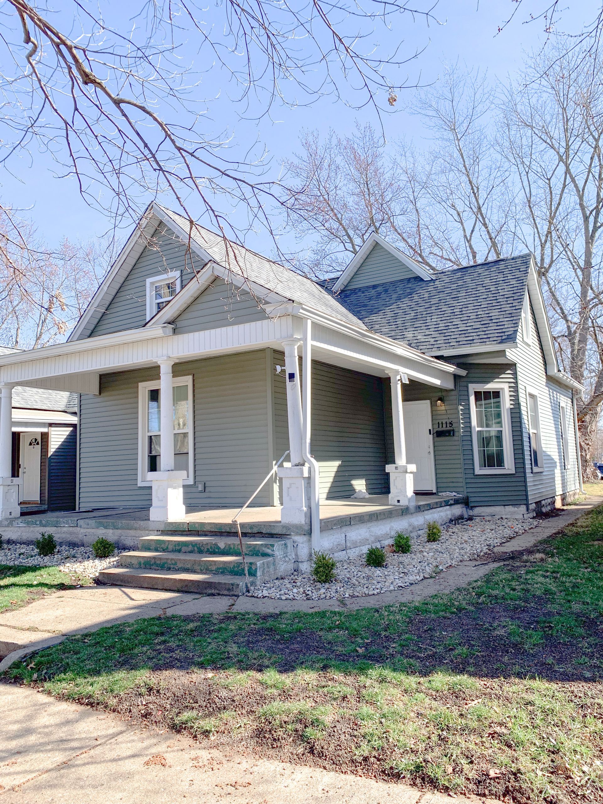 A small house with a porch and stairs on a sunny day.