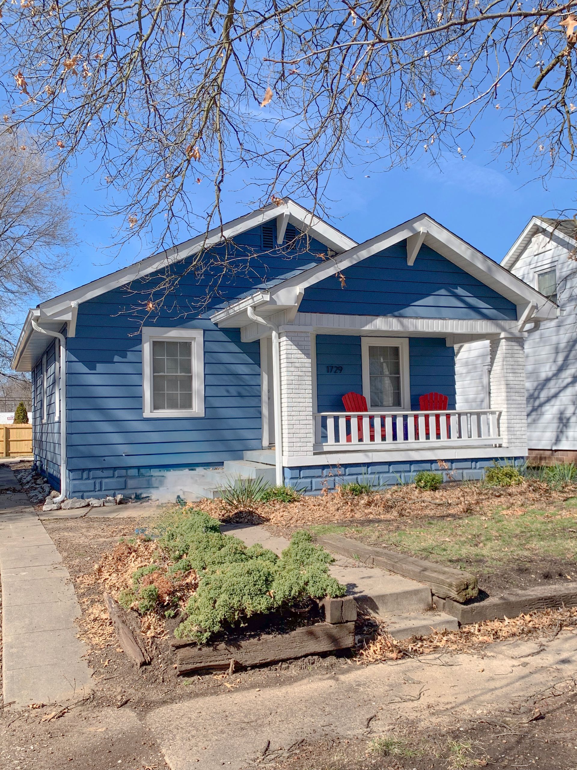 A blue and white house with a red chair on the porch.