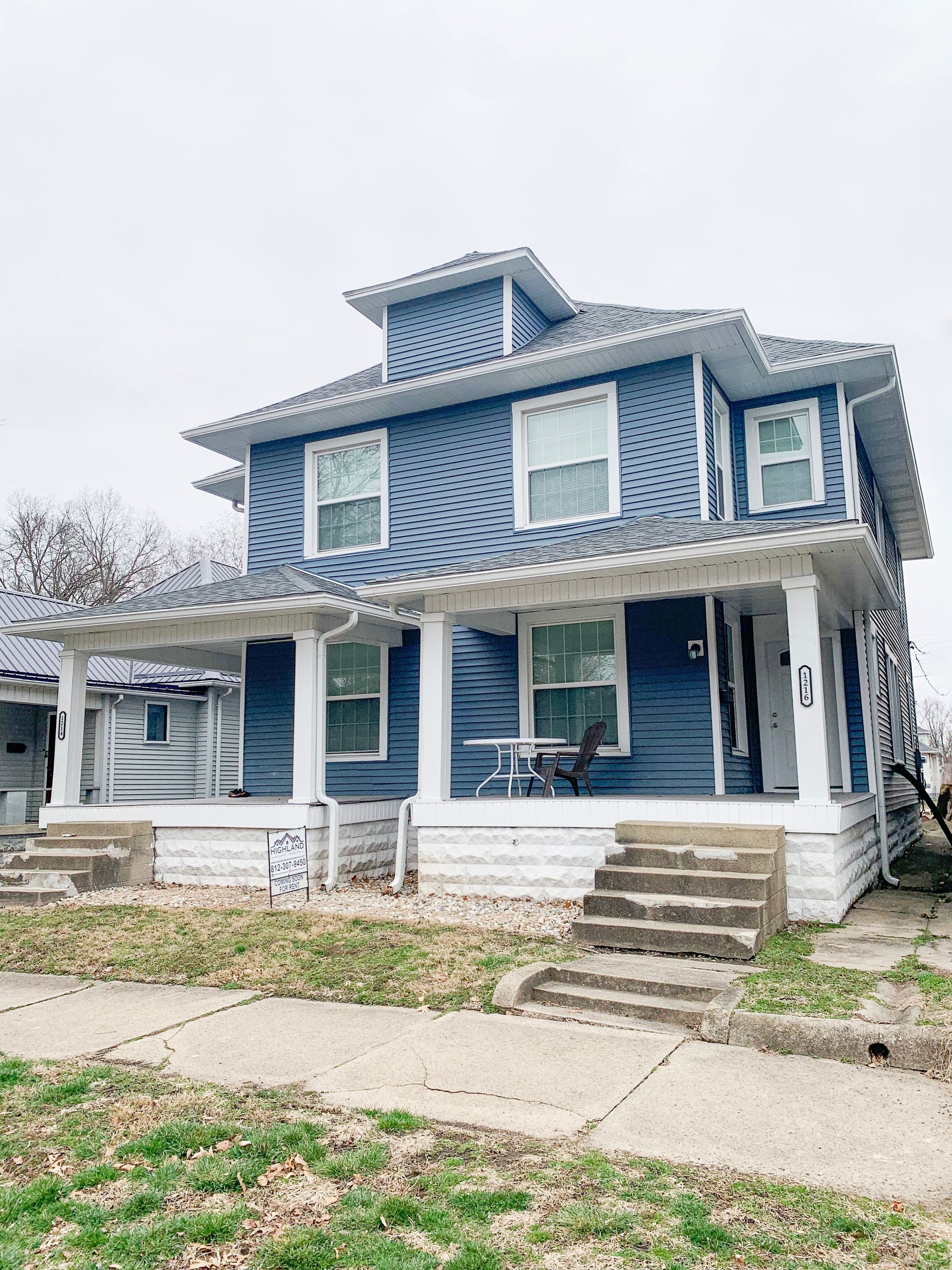 A blue and white house with a porch and stairs