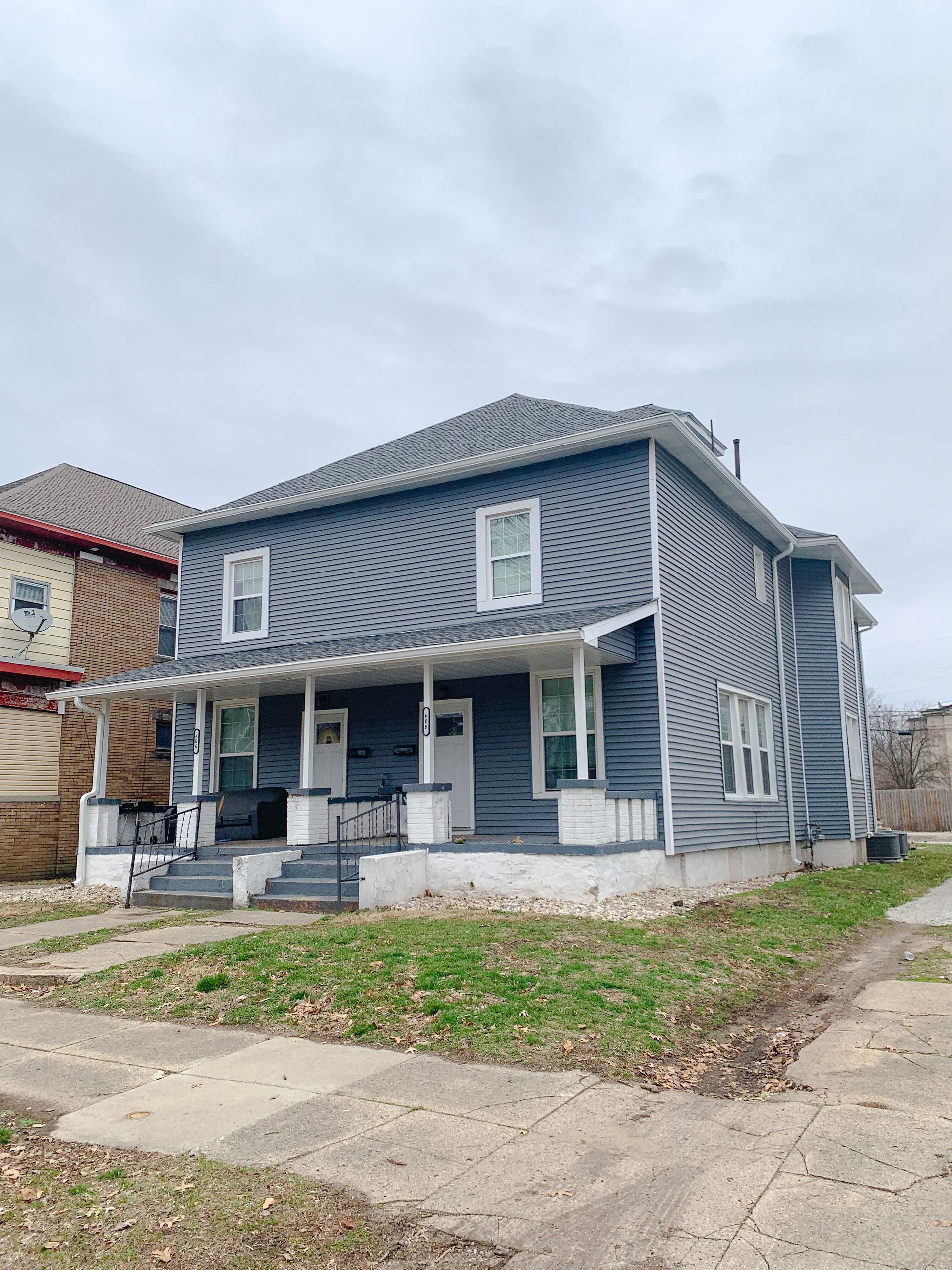 A blue house with a porch and stairs in a residential area.