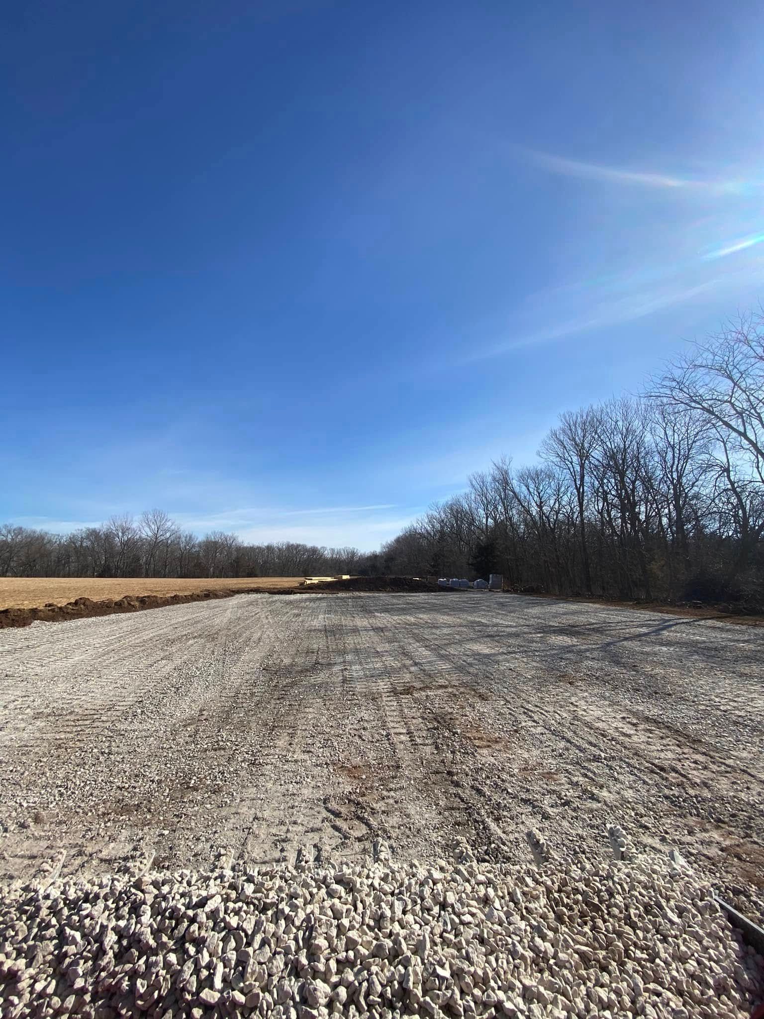 Wide gravel path beside bare trees under a bright blue sky on a clear day