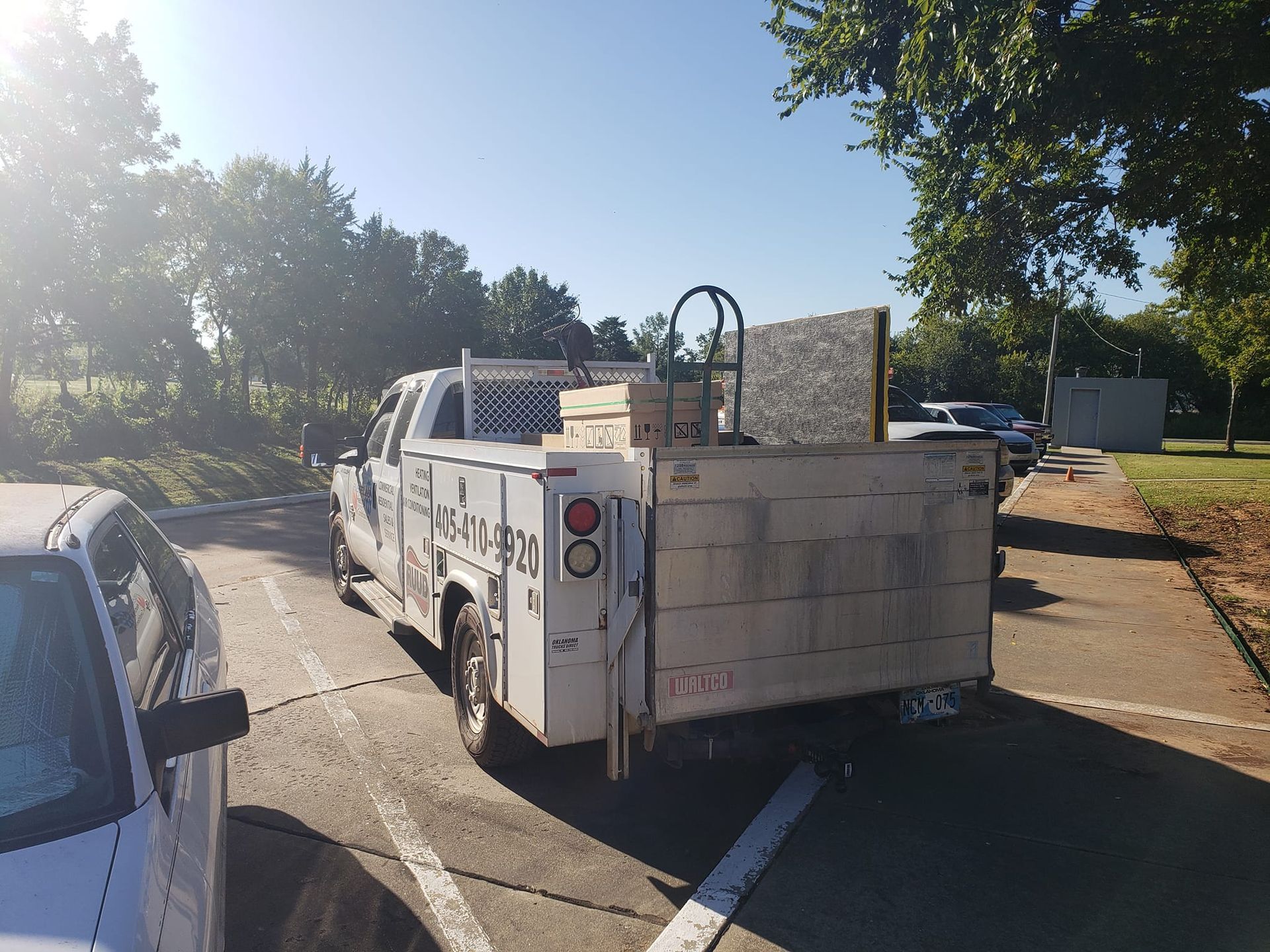 White work truck parked outdoors, loaded with materials, on a sunny day.