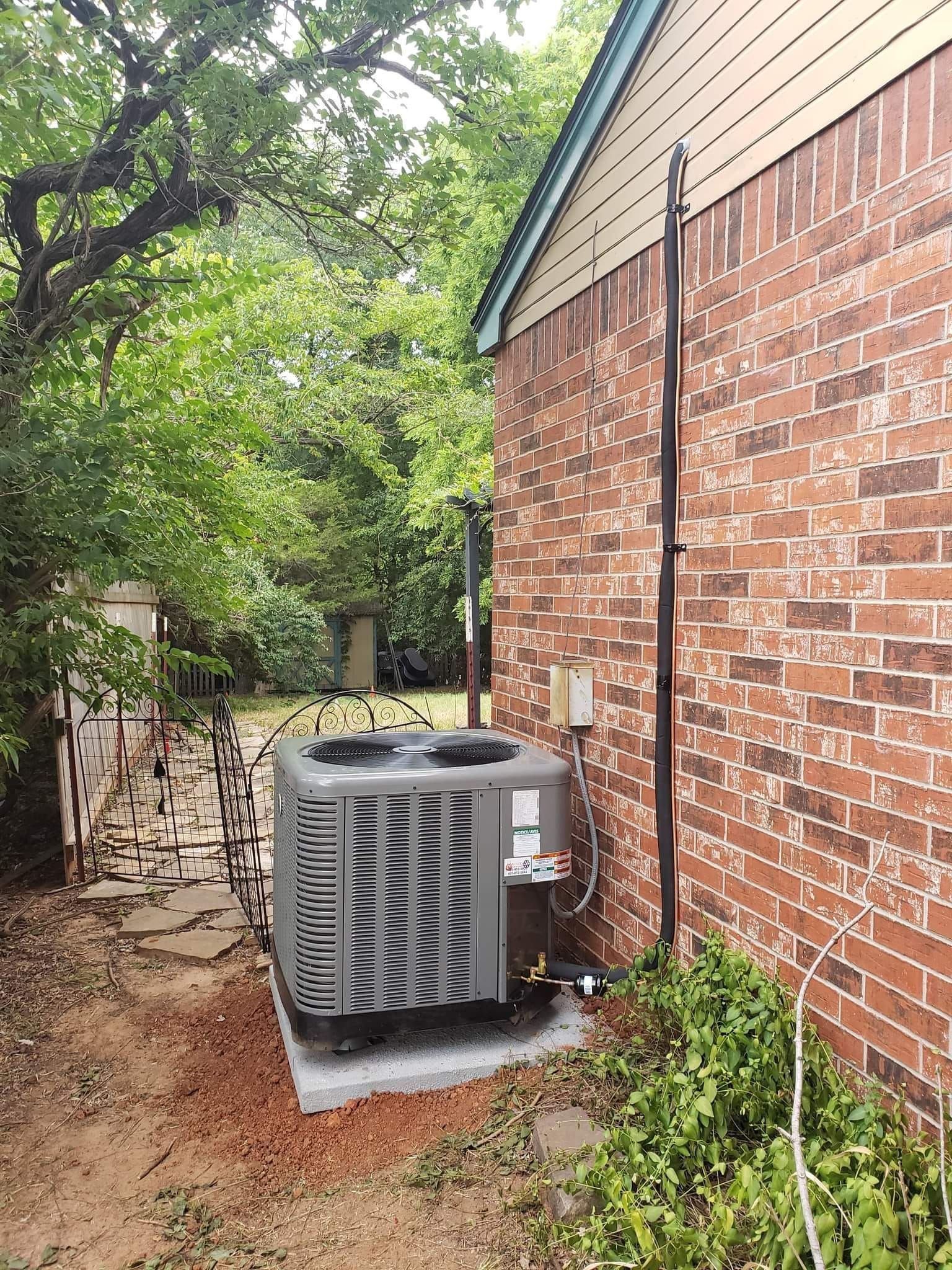 An air conditioning unit sits next to a brick building.