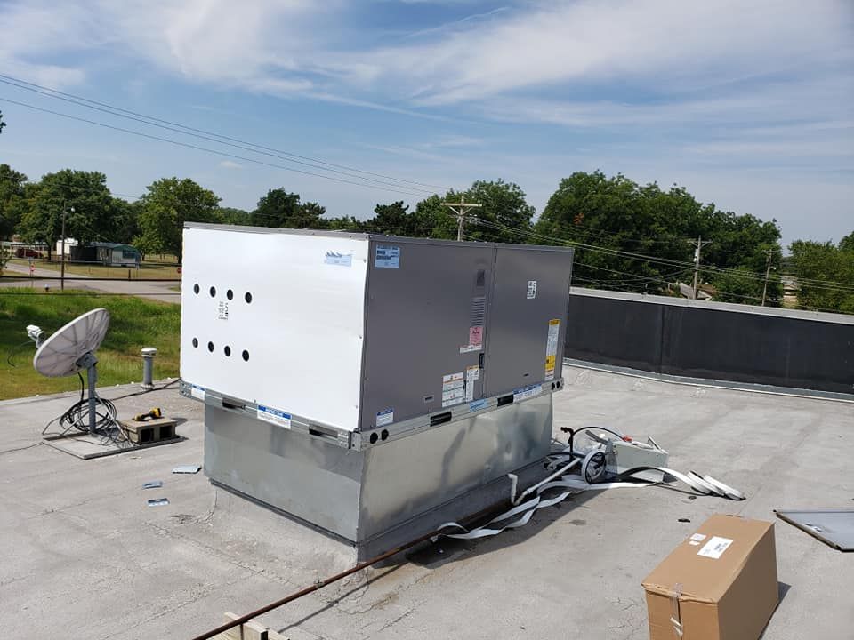 HVAC unit on a rooftop, white and gray metal with vents, sunny day.