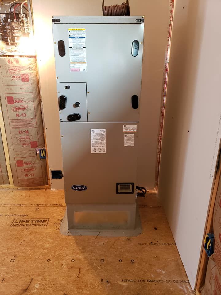 An HVAC unit in a room with unfinished drywall and wooden flooring.