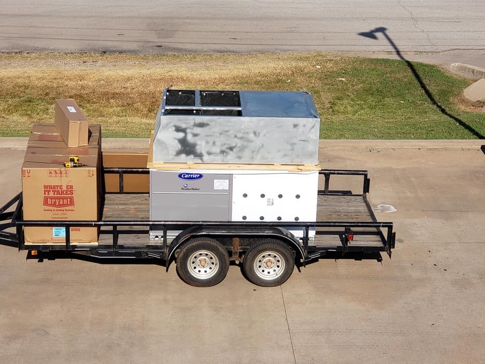 Trailer with HVAC equipment: Carrier unit, boxes, and metal components on a trailer parked outside.