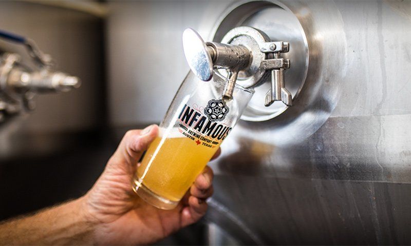 craft beer being poured into an Infamous Brewing pint glass
