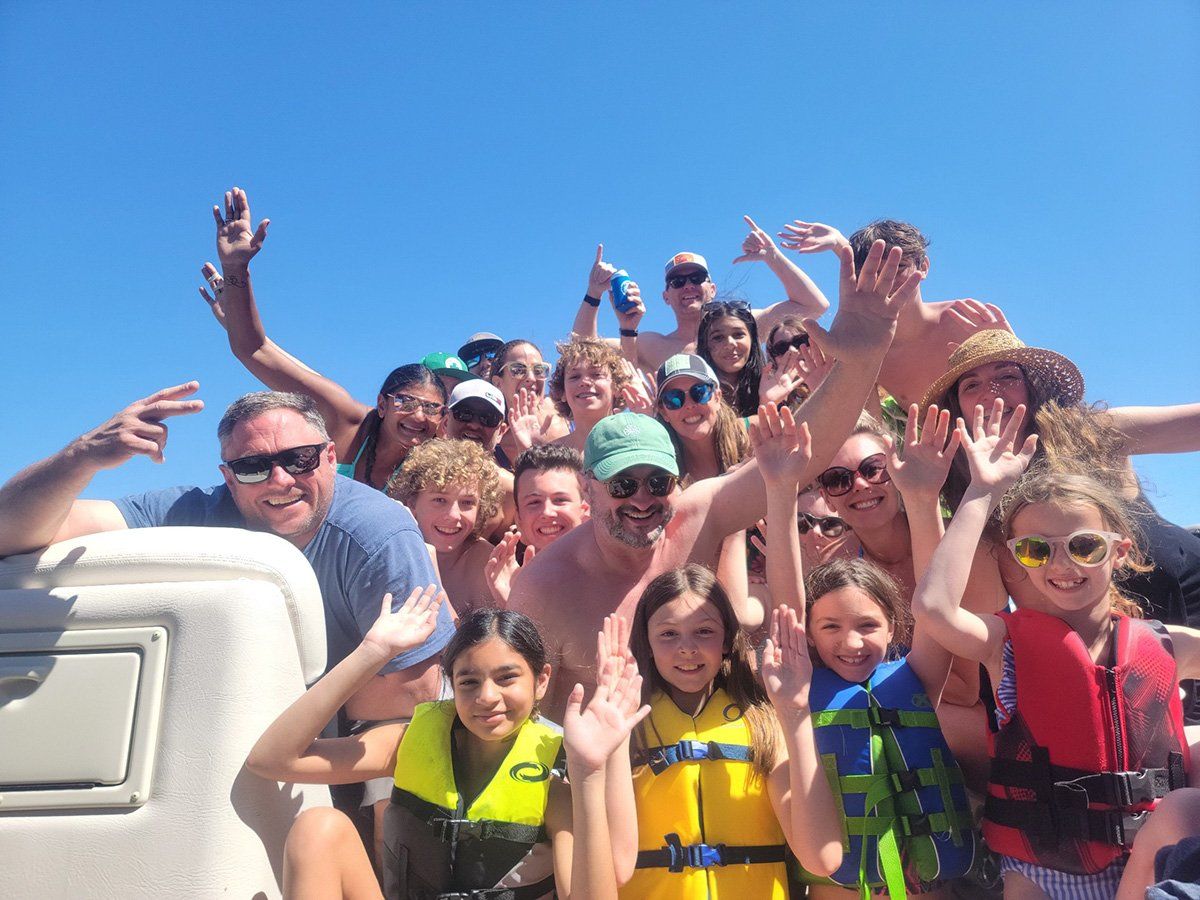 friends and family gathered for a group photo on a party boat during a kids birthday party
