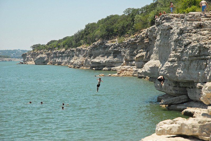 people cliff jumping into the water at Pace Bend Park
