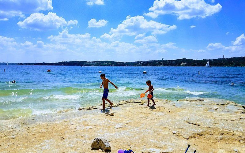 Two kids having fun on the shore at Windy Point Park in Lake Travis