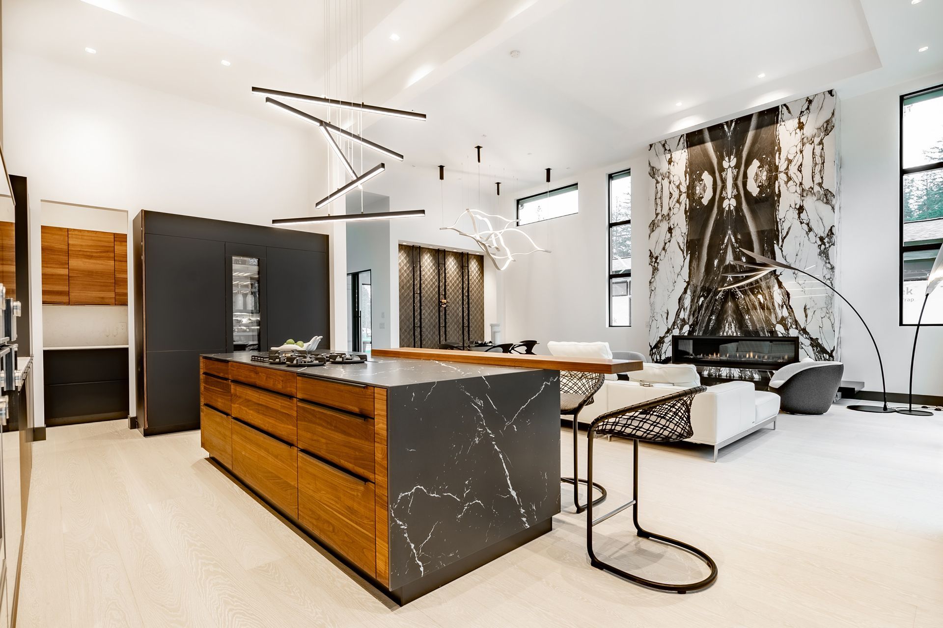 Modern kitchen with wood island and dark countertop, bright interior, decorative lighting, and artwork.