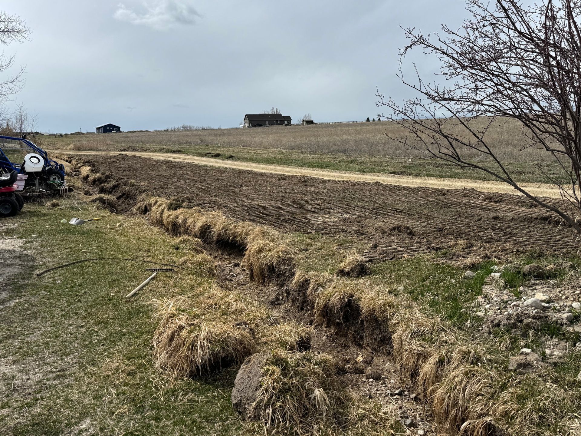 A car is parked on the side of a dirt road in a field.