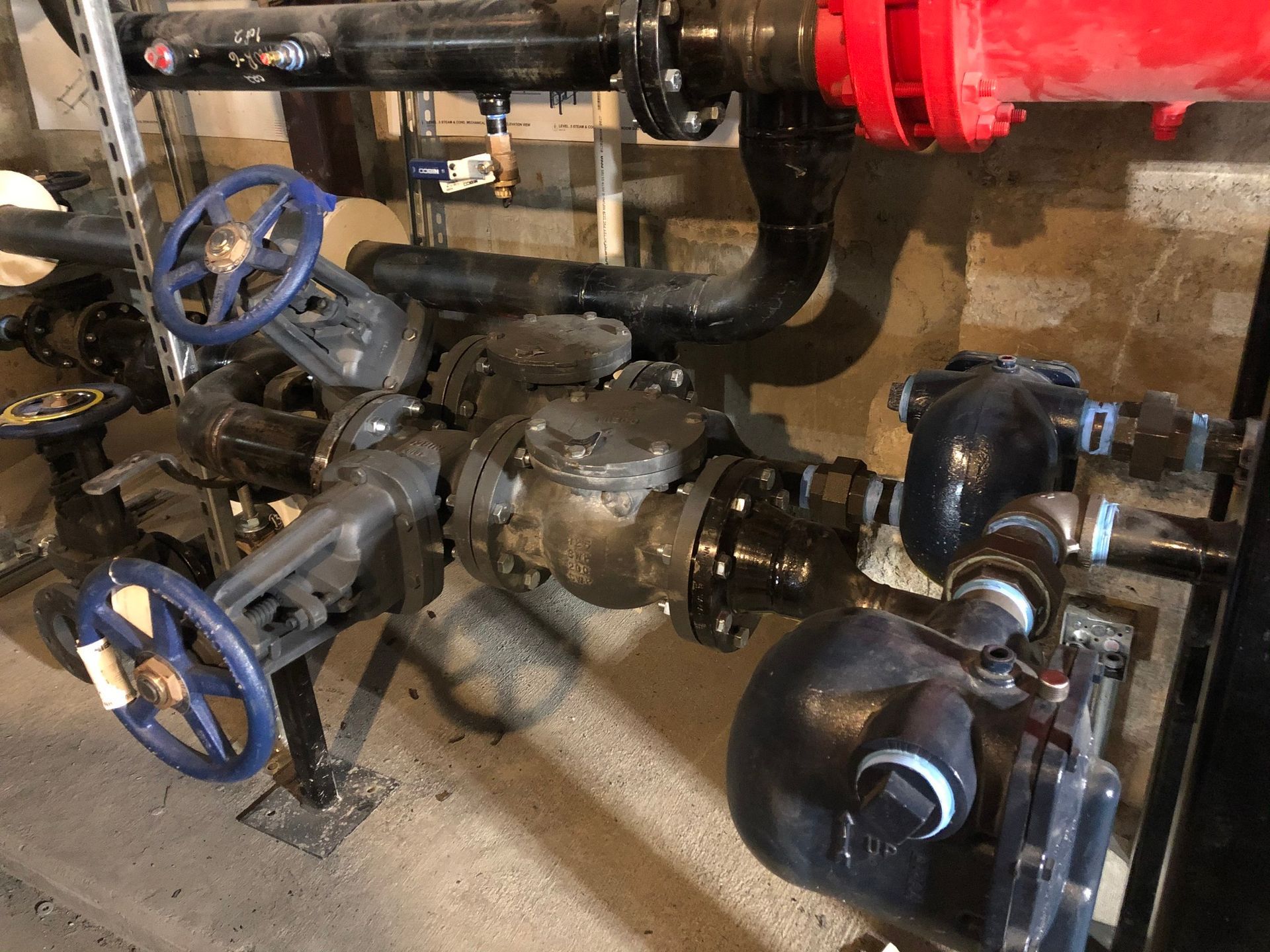 A bunch of pipes and valves are connected to each other in a room.