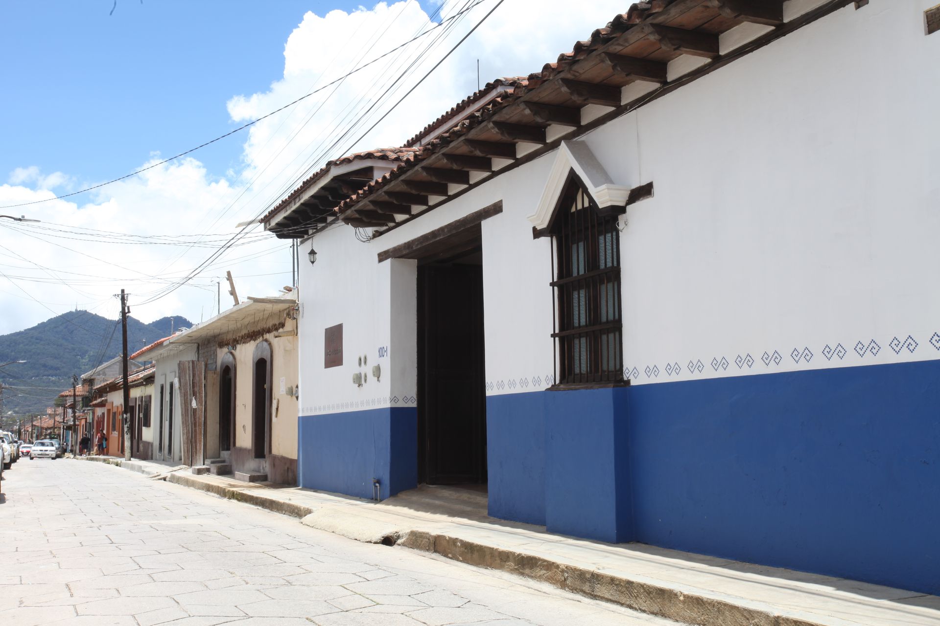 Un edificio azul y blanco con una ventana en el costado.