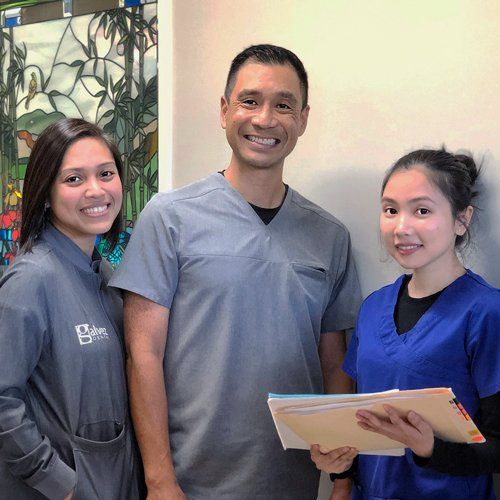 A man and two women in scrubs are posing for a picture.