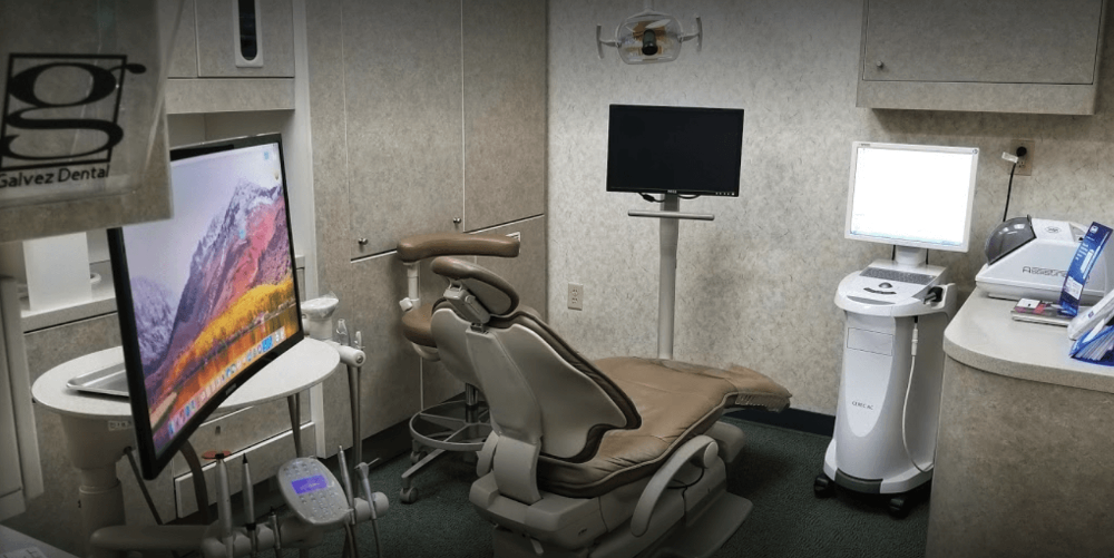 A dental office with a dental chair and a computer monitor.