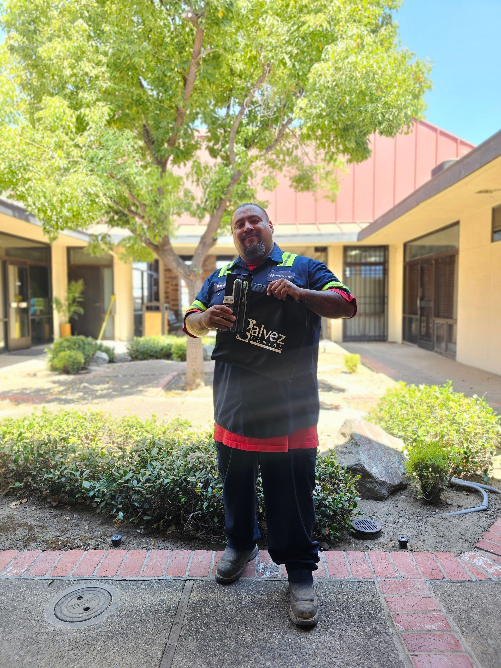 A man is standing in a courtyard holding a bottle of beer.