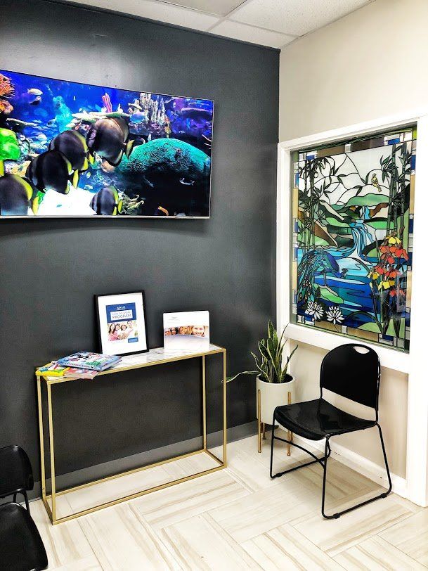 A waiting room with a table and chairs and a painting on the wall.