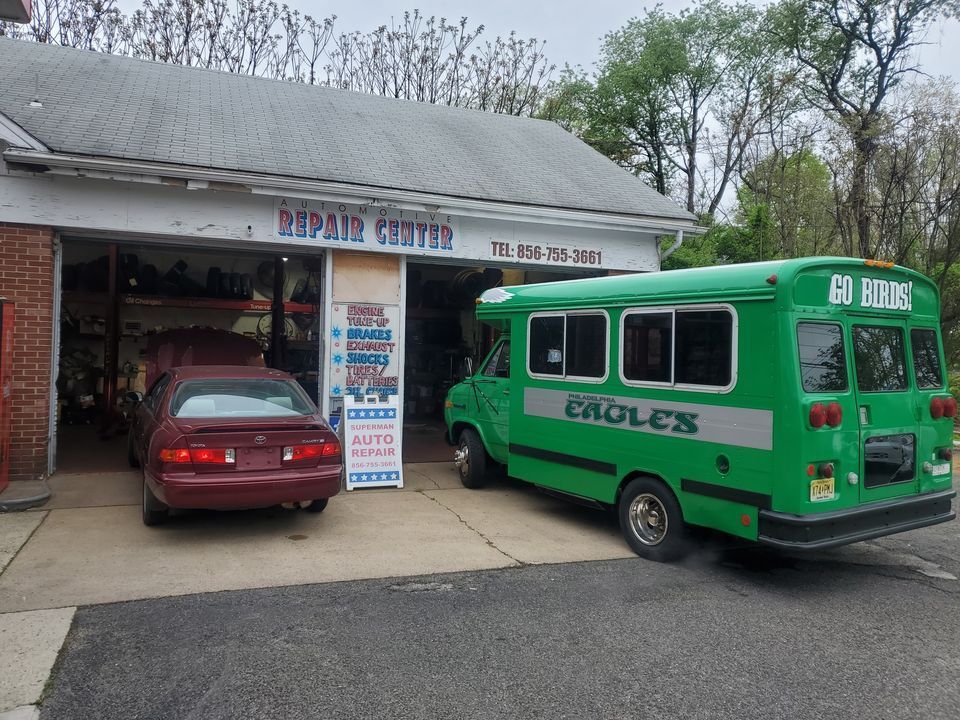 A green school bus is parked in front of a repair center
