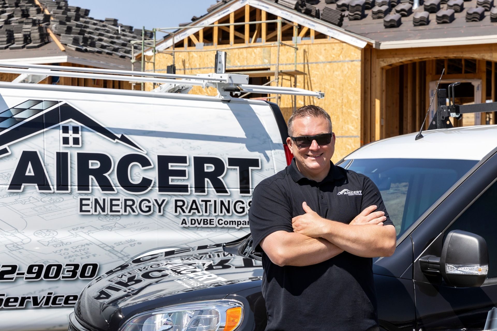 A man is standing in front of two aircert energy ratings vans.