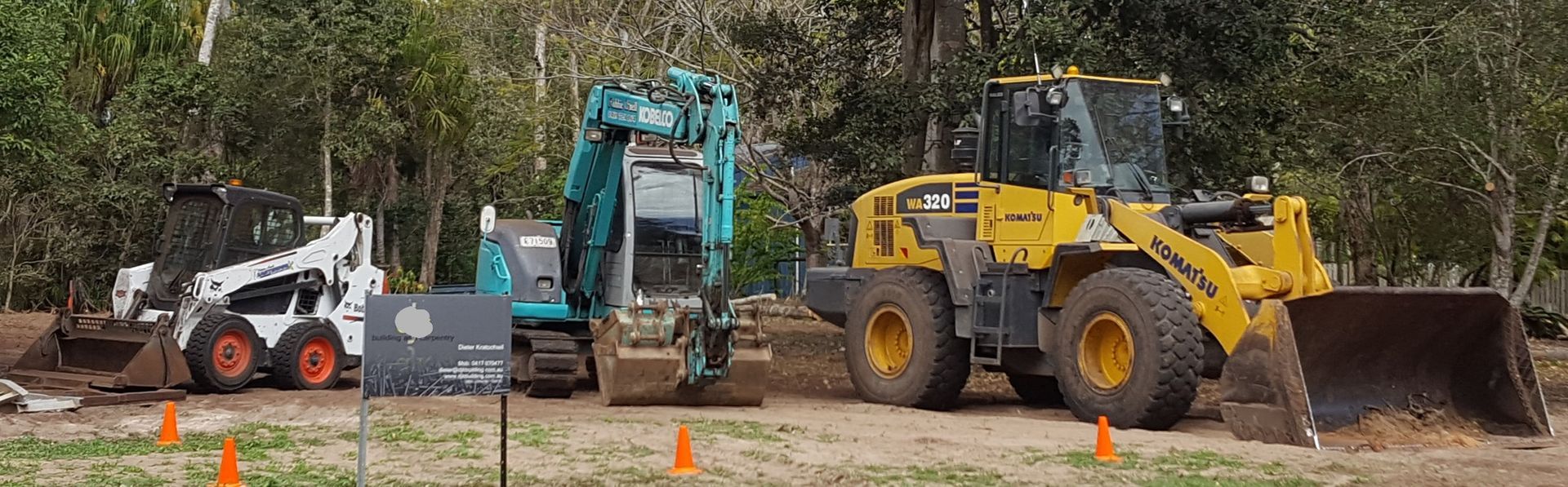 Three pieces of construction equipment: a skid steer loader, an excavator, and a wheel loader, lined up on a construction site. — Snell Earthworx In Craignish, QLD