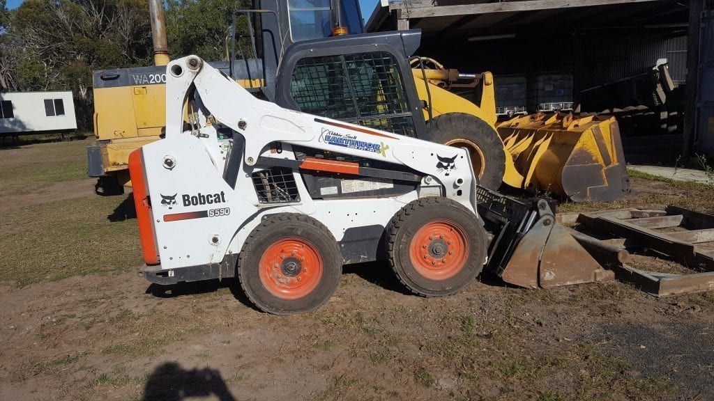 A White Bobcat Skid-steer Loader With Orange Wheels Sits Outside — Snell Earthworx In Craignish, QLD