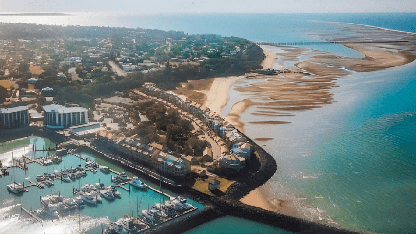 Aerial view of coastal town with marina, beach, and bridge over turquoise water — Snell Earthworx In Craignish, QLD