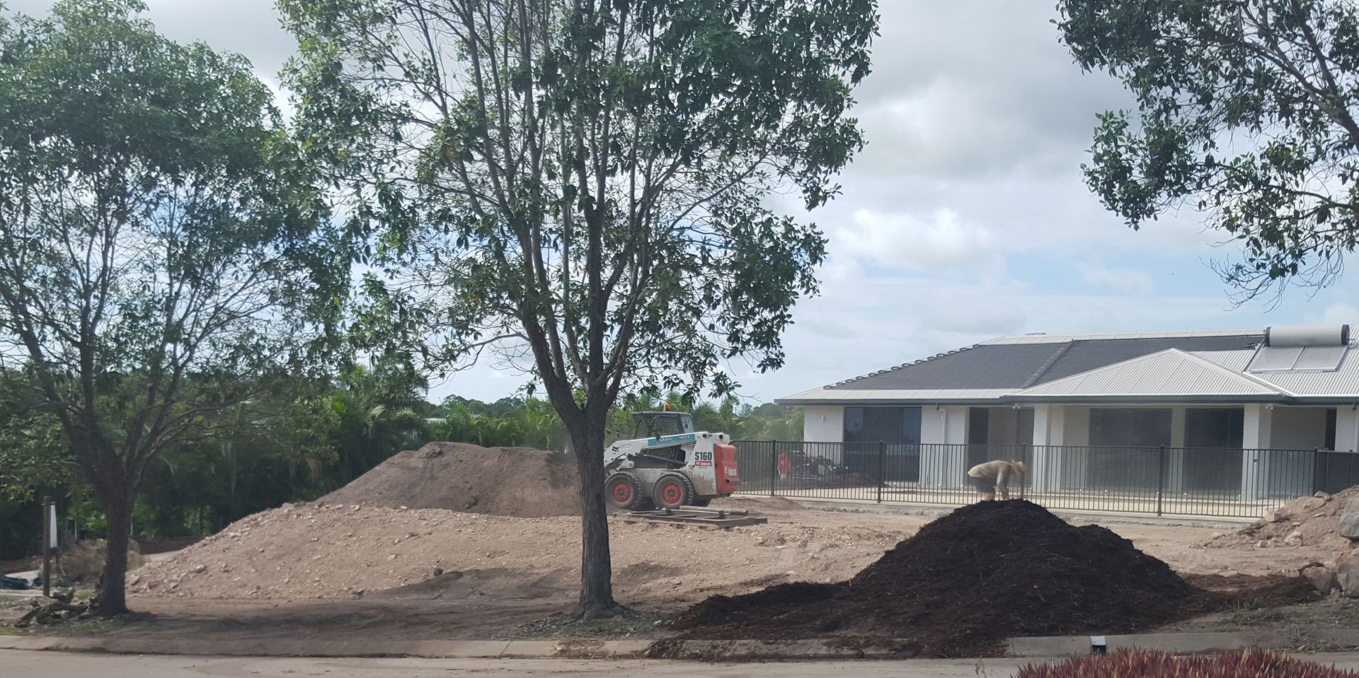 Construction Site with House, Trees, Dirt Piles, and a Small Vehicle — Snell Earthworx In Craignish, QLD