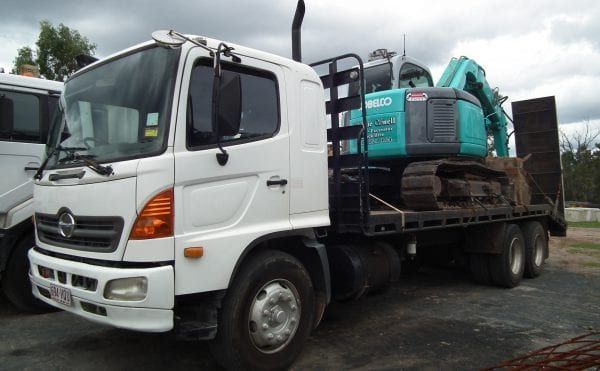 White Truck Hauling a Teal Excavator — Snell Earthworx In Craignish, QLD
