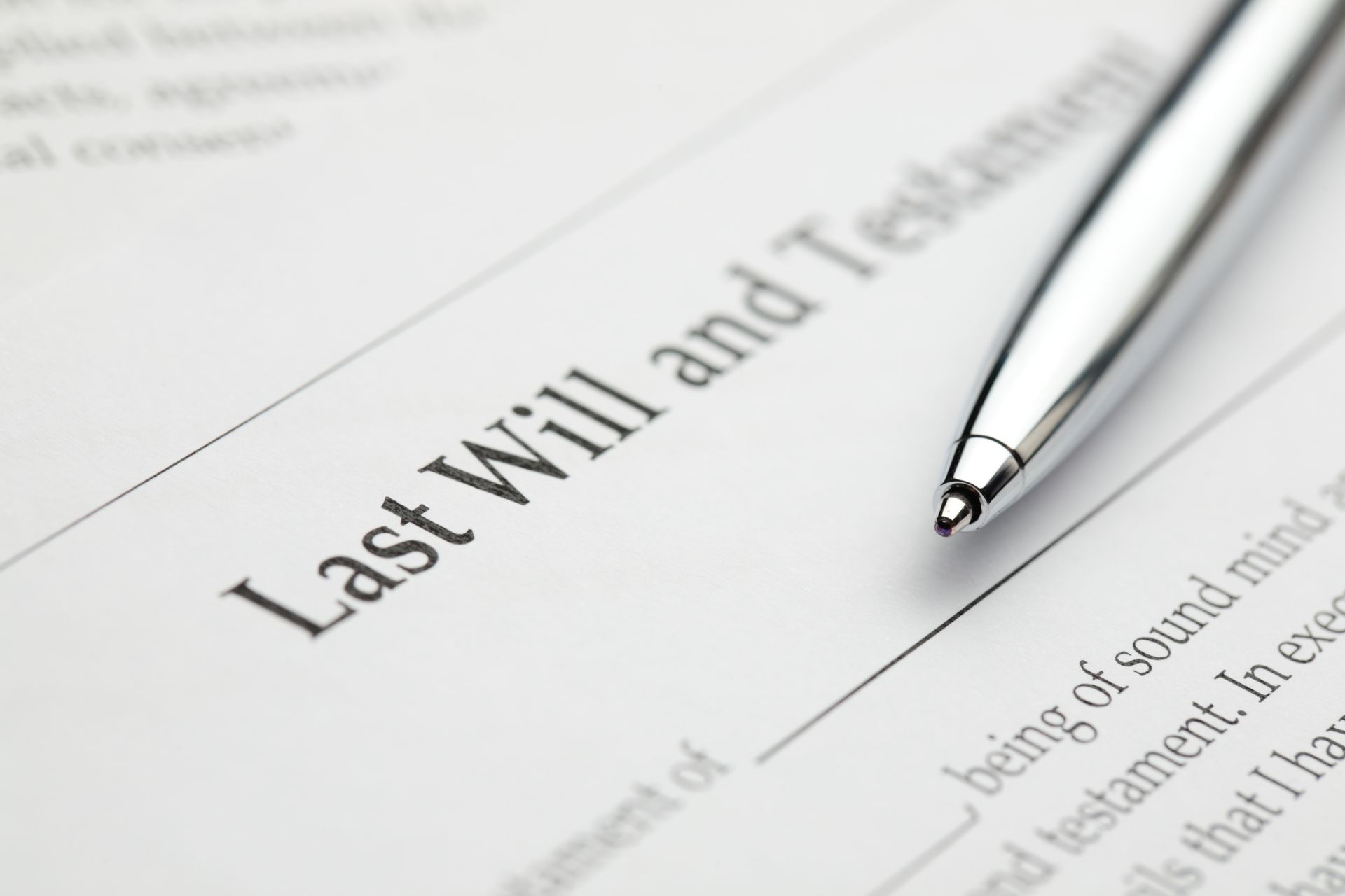 A silver ballpoint pen rests on a legal document titled Last Will and Testament. A silver ballpoint pen rests on a legal document titled Last Will and Testament.