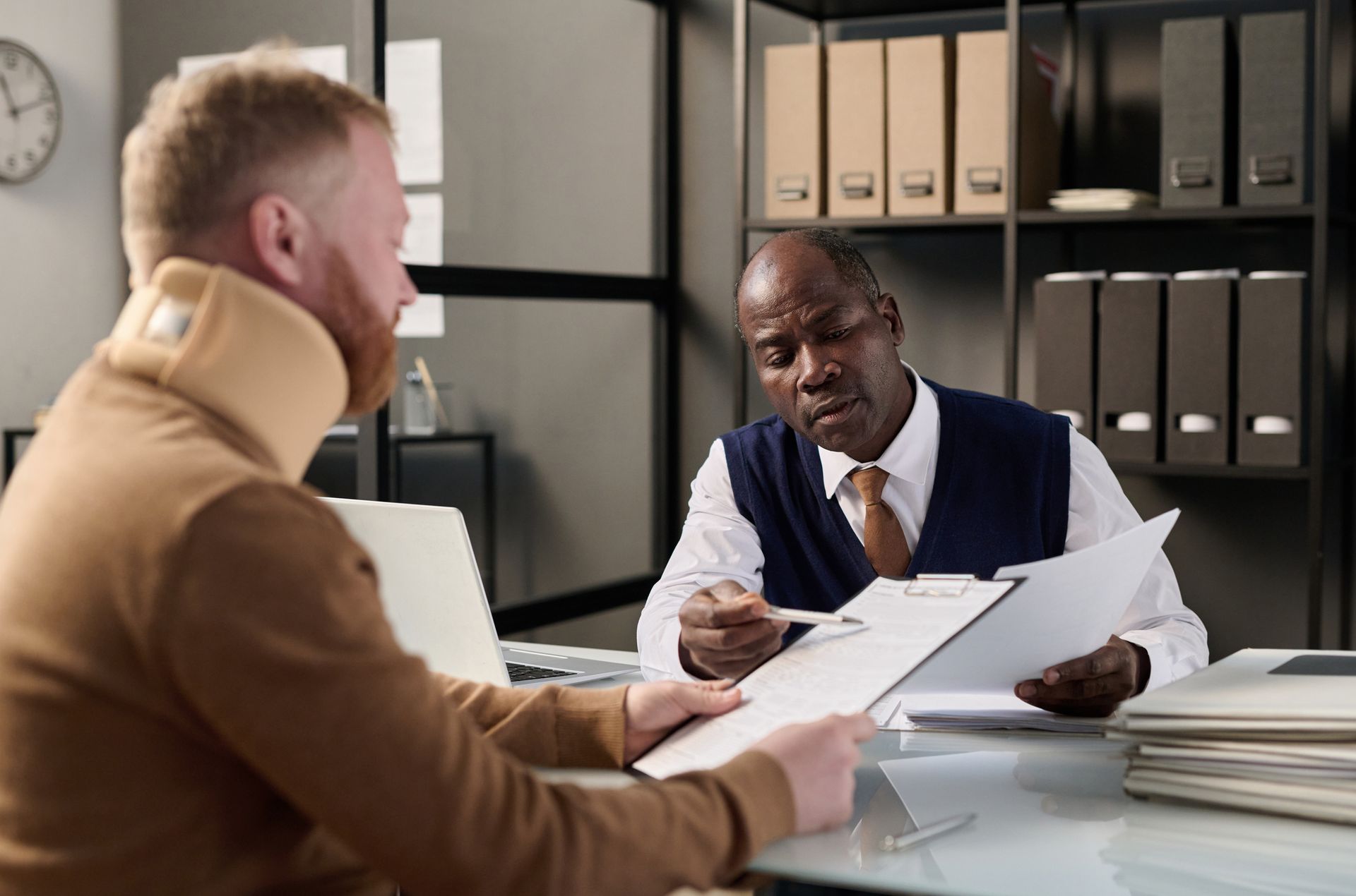 A neck brace man meets with a lawyer in a suit at Maxwell Law Firm, a personal injury attorney in 
B