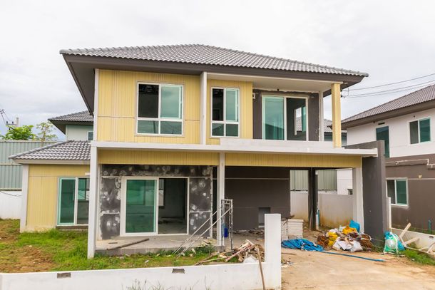 A man is paving a driveway in front of a house.