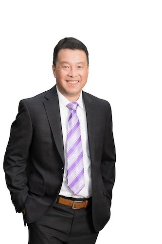 A woman is sitting at a desk with a laptop and a vase of flowers.