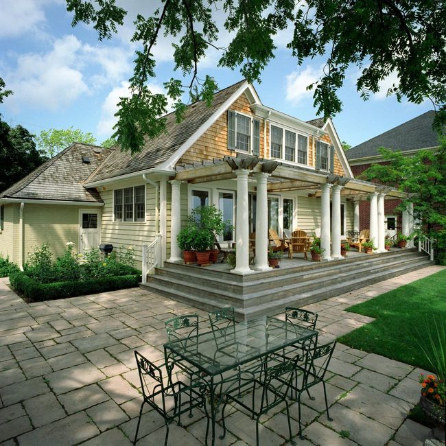 House with patio, columns, and green metal patio furniture on a sunny day.
