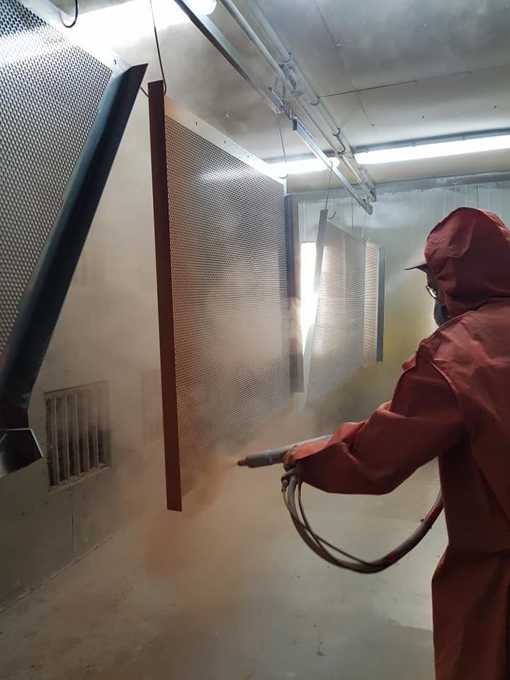 A Man In A Red Suit Is Spraying Powder On A Wall — Border Security Doors & Powder Coating in Wodonga, VIC